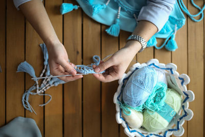 Craftswoman knits and assembles the braid, close-up. real light interior, wooden table, top view. 