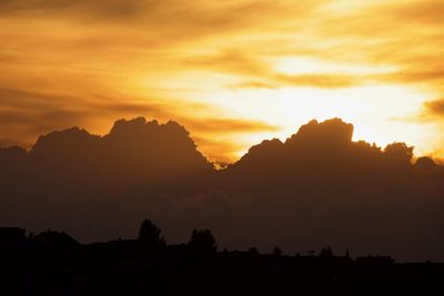 Scenic view of silhouette mountains against orange sky