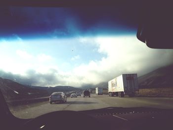 Road passing through mountains against cloudy sky