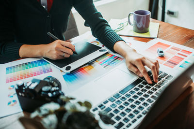 Midsection of businesswoman working at desk in office