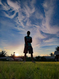 Rear view of man standing on field against sky