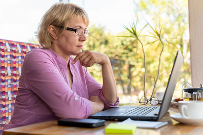 Young woman using mobile phone while sitting on table
