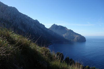 Scenic view of sea and mountains against blue sky