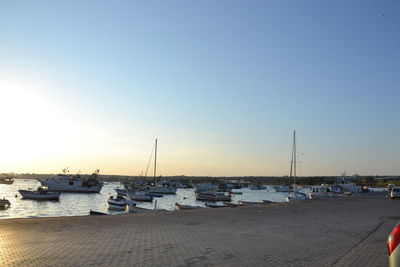 Boats moored in harbor at sunset