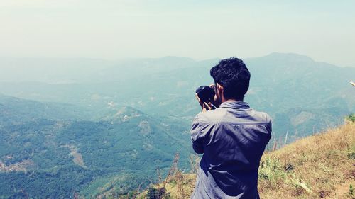 Rear view of man photographing on mountain