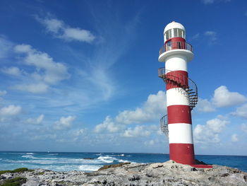 Lighthouse by sea against sky