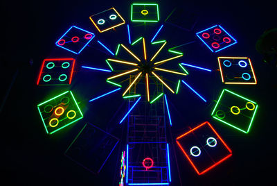 Low angle view of illuminated lighting equipment against black background