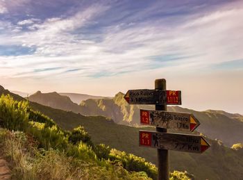 Information sign on mountain against cloudy sky