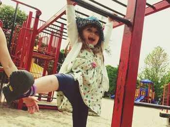 Happy girl playing at jungle gym in park