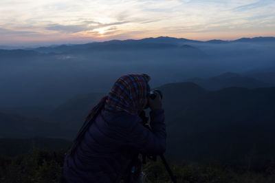 Man standing on mountain against cloudy sky