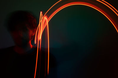 Defocused image of man standing in dark with light painting