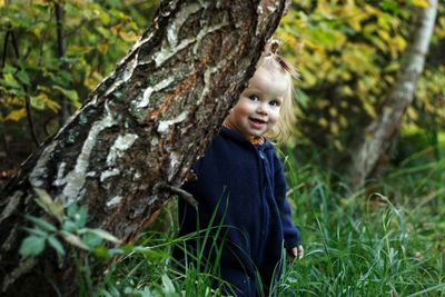 Portrait of smiling boy on tree trunk