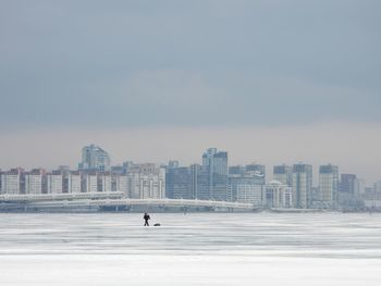 Man by buildings against sky in city during winter