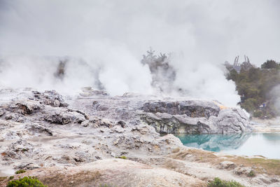 Scenic view of hot spring against cloudy sky