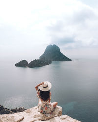 Rear view of woman standing by sea against sky