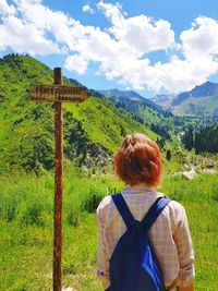 Rear view of woman looking at mountain against cloudy sky