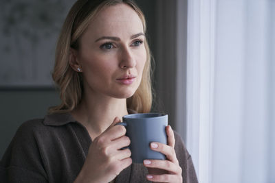 Thoughtful woman having coffee at home