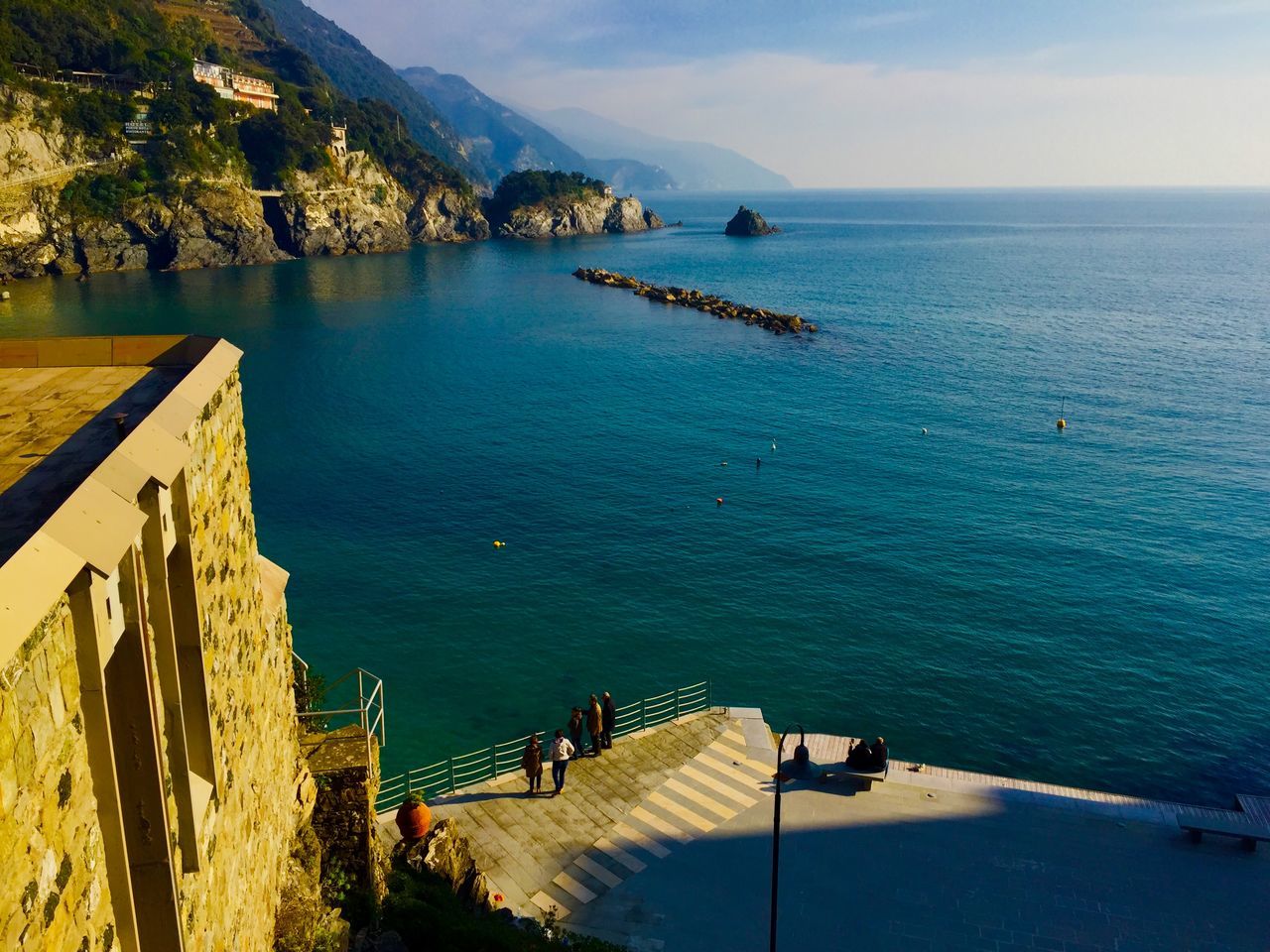 sea, water, tranquil scene, tranquility, railing, horizon over water, scenics, beauty in nature, sky, blue, mountain, nature, idyllic, pier, high angle view, tree, built structure, the way forward, beach, sunlight