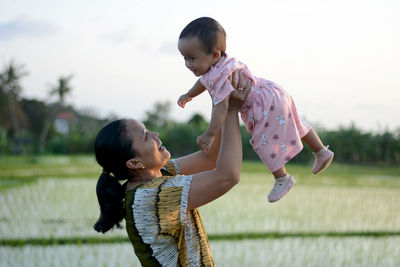 Side view of mother carrying daughter