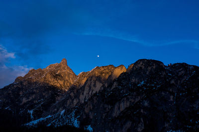 Low angle view of rocky mountains against blue sky