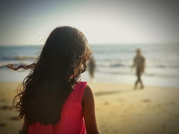 Rear view of woman at beach against sky