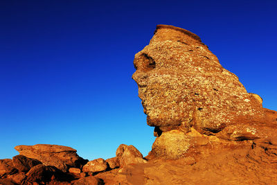 Sphinx rock formation against clear blue sky at bucegi natural park