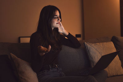 Young woman using mobile phone while sitting on sofa at home