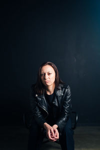 Portrait of beautiful young woman against black background