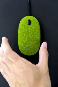 Close-up of man holding leaf over black background