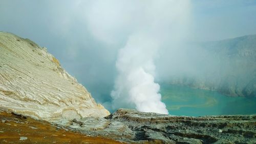 Geyser emitting from volcanic mountain against sky