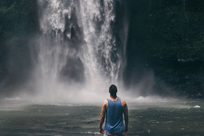 Rear view of man standing by waterfall