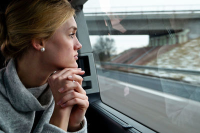 Young thoughtful woman looking through window in car