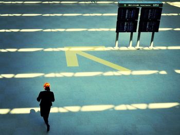 High angle view of business person walking next to arrow symbol
