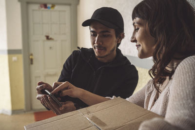 Smiling customer signing on smart phone during package delivery
