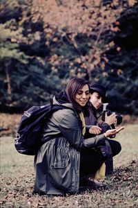 Female friends with backpack crouching on land