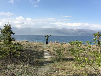 Mature man with arms outstretched standing by lake