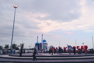 People on street by mosque against sky