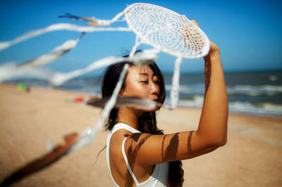 Asian girl holding dream catcher on beach