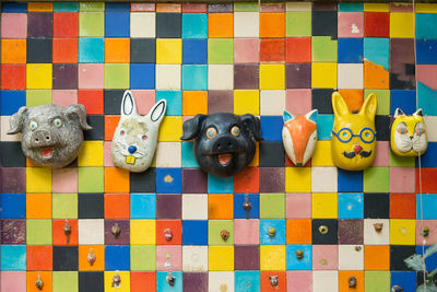 Close-up of animal toys mounted on multi colored tiled wall