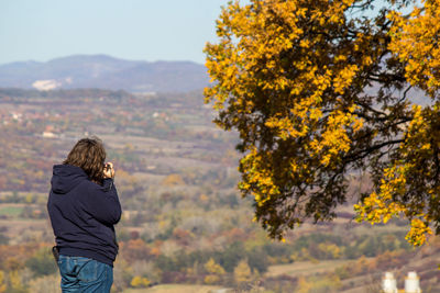 Rear view of man standing by tree on mountain