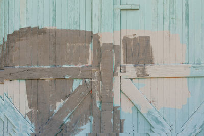 Wooden gate made of planks, randomly painted in mint, beige and brown colors