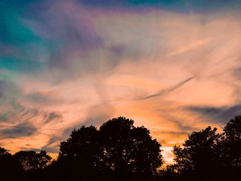 Low angle view of silhouette trees against dramatic sky