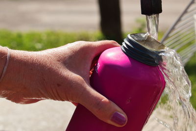 Close-up of hand holding pink bottle