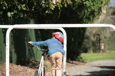 Rear view of boy with umbrella against trees