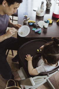 High angle view of father feeding baby son at home