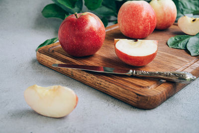 Front view of freshly harvested ripe red organic apples on wooden cutting board on table.