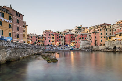 Historic buildings at sea shore in liguria against sky