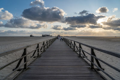 Pier over sea against sky during sunset