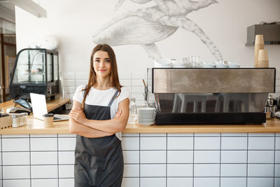 Portrait of young woman standing against wall