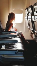 Side view of girl sitting in airplane